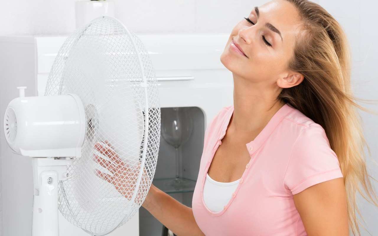 Mujer refrescándose con el ventilador